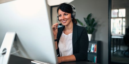 Female cold call professional smiling while on call with headset 